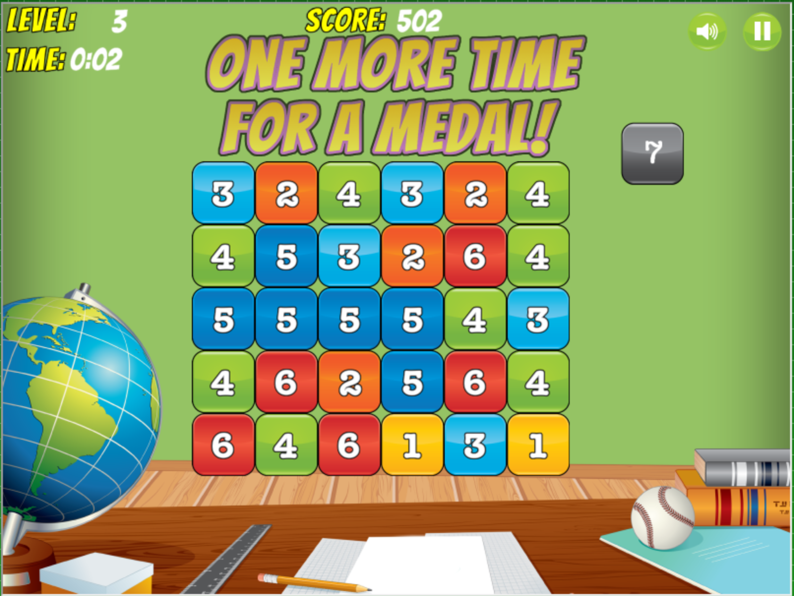 Screenshot of a puzzle game with a grid of numbered blocks and the message "One More Time for a Medal!" shown at the top. The game is at Level 3 with a score of 502 and a timer showing 0:02. A globe, ruler, and baseball are on a desk below the grid.